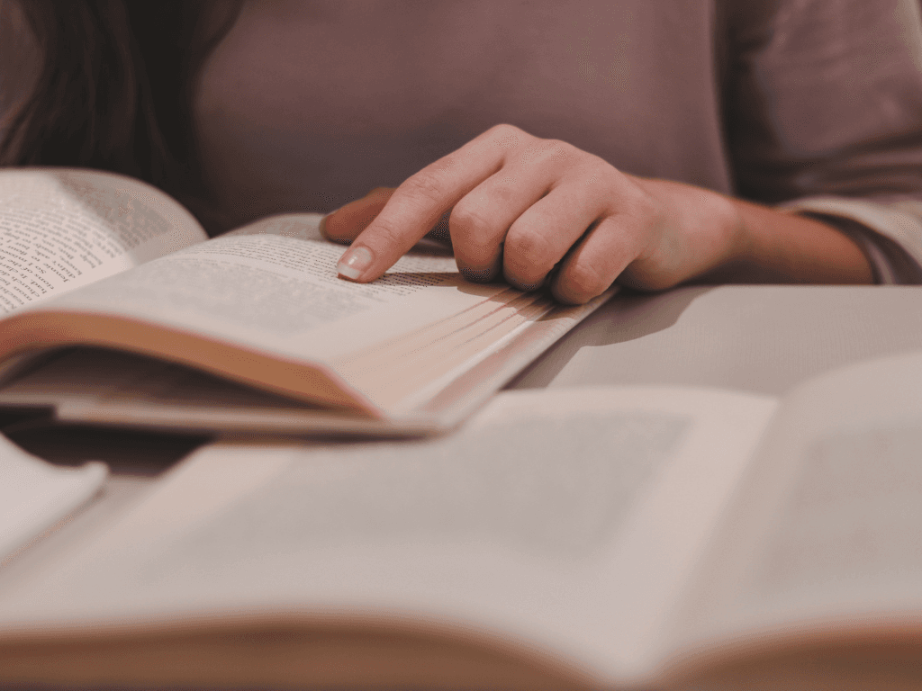 Una mujer está sentada en una mesa leyendo un libro.